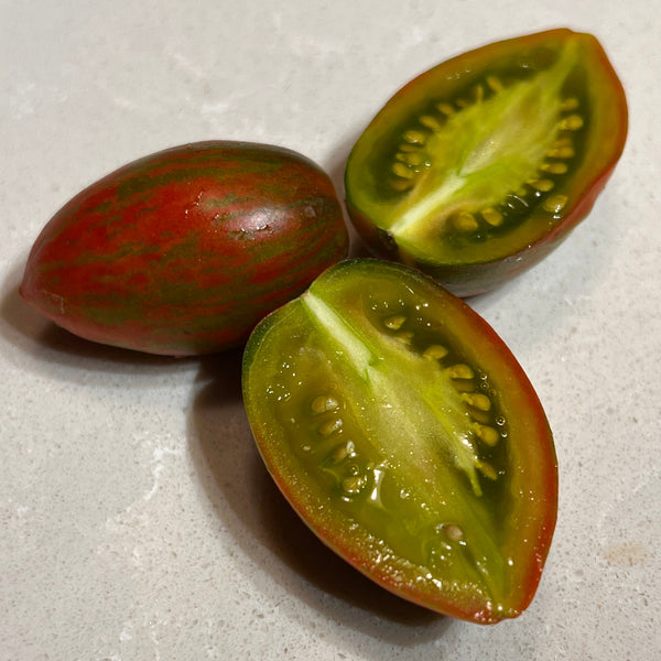 Three red and green tomatoes on a light gray surface
