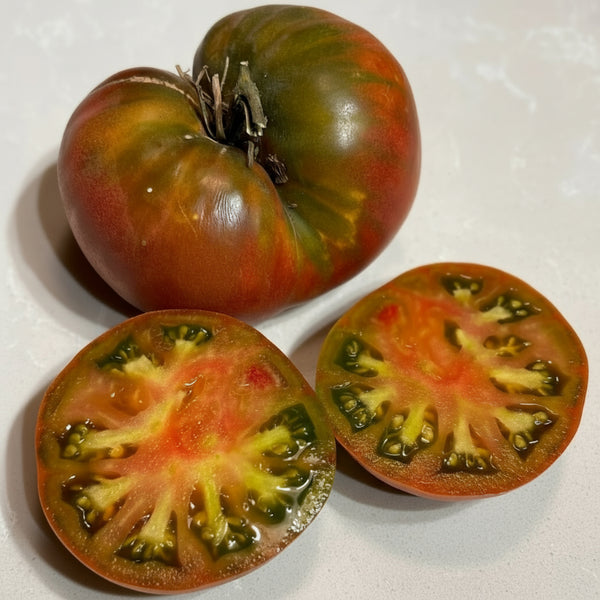 Whole and sliced heirloom tomato on a white surface